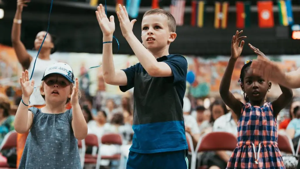 Kleine Kinder klatschen bei einer musikalischen Aktivität im Kinderbereich eines Kulturfestivals.