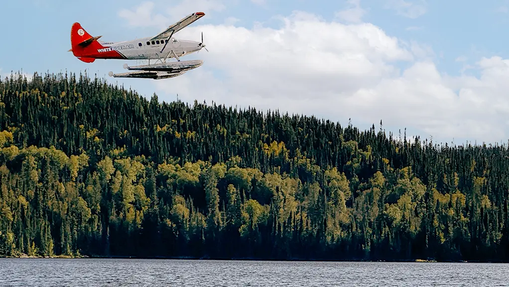 Hydravion planant au-dessus d’un lac bordé d’une vaste forêt qui transporte des chasseurs dans un lieu de chasse éloigné dans le Nord de l’Ontario.