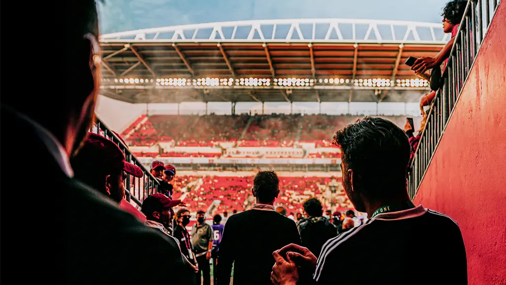Soccer players walking through a stadium tunnel toward the field before a match.