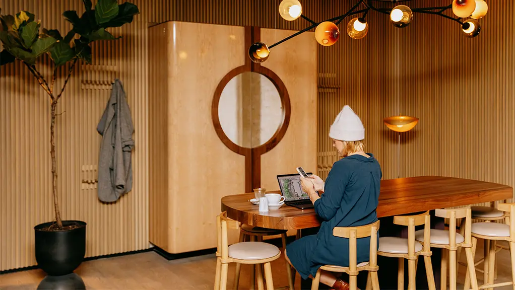 Persona trabajando en un escritorio en una habitación con paneles de madera e iluminación moderna.