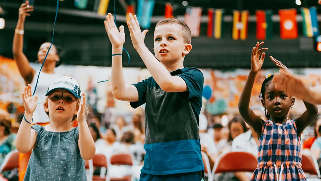 Niños pequeños aplauden durante una actividad musical en la zona infantil de un festival cultural.