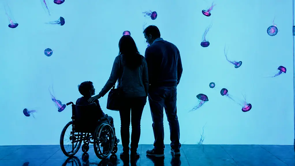 Family with a child using a wheelchair viewing the jellyfish exhibit at Ripley’s Aquarium of Canada in Toronto.