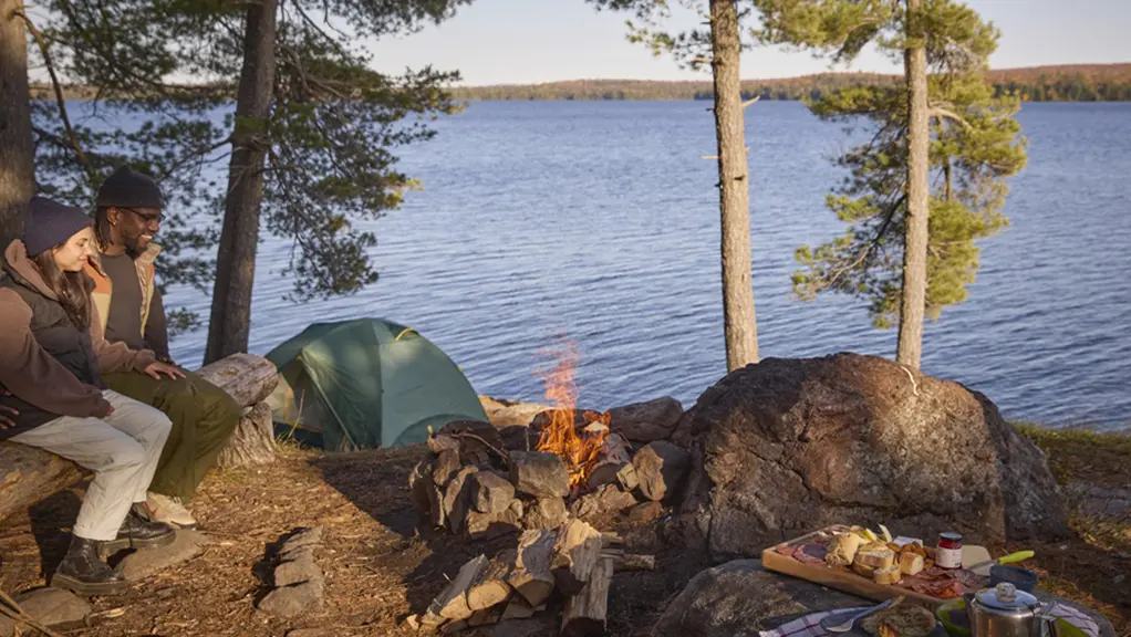 Two people sit together in front of a fire at a campsite in Algonquin Park.