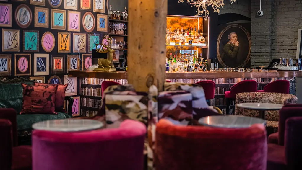 Intérieur de Secrette, un bar caché de Toronto, avec des chaises en velours, des œuvres d’art éclectiques et une ambiance chaleureuse et colorée.