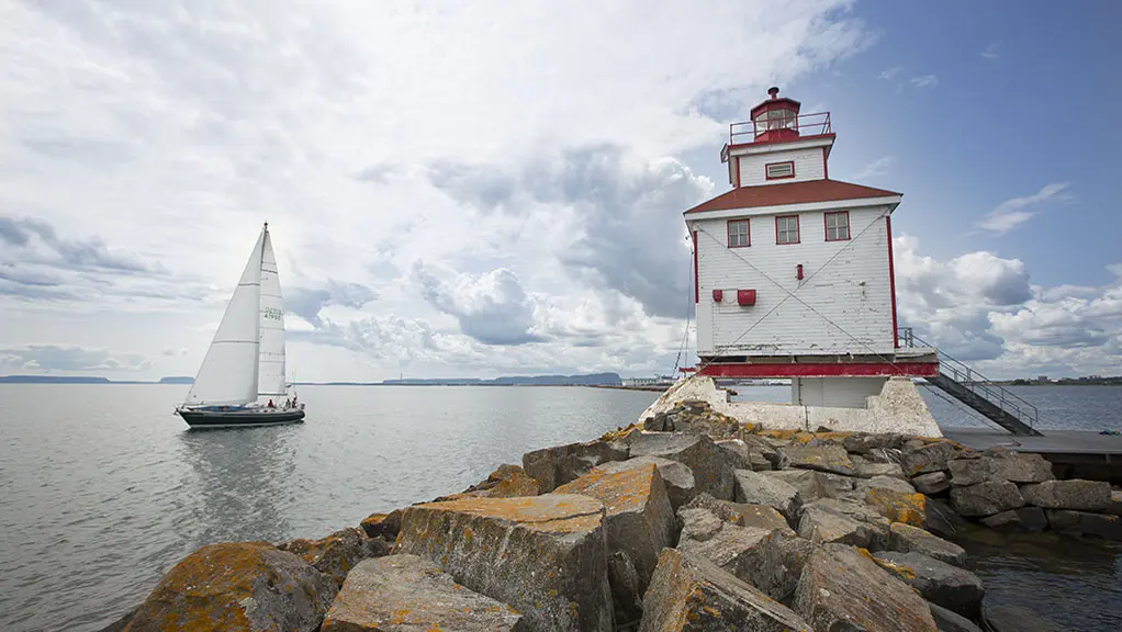 Un phare se trouve sur une péninsule surplombant un lac.