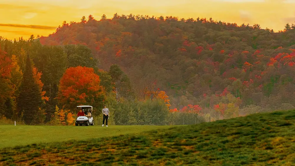 Golfer genießen die Golfsaison im Herbst auf üppigen Fairways vor der Kulisse herrlicher Herbstfarben.