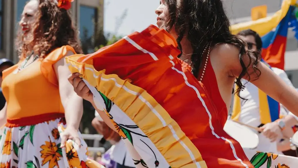 Women dressed in colourful orange and red print dance during the summer salsa festival in Toronto.
