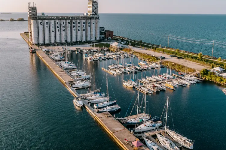 Aerial view of Collingwood’s harbourfront with the historic grain terminals, sailboats docked in a marina, and Georgian Bay stretching into the horizon.