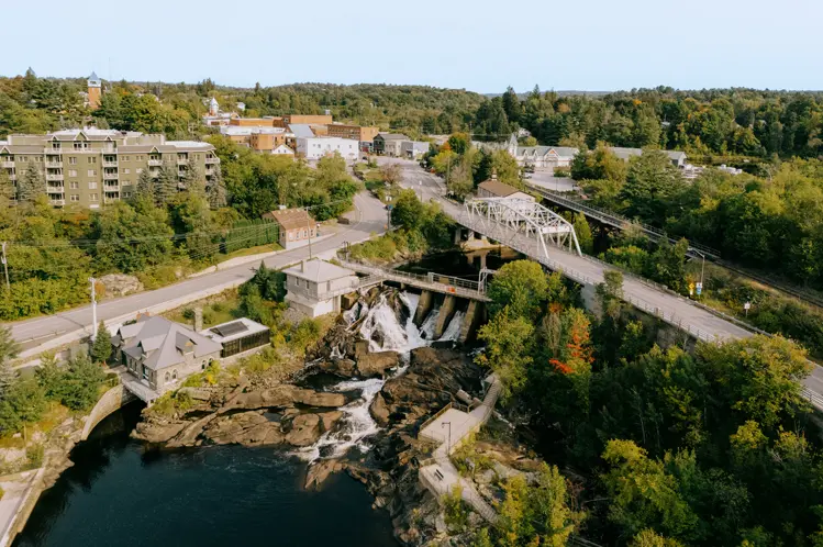 美しい橋、滝、森林地帯と町の建物が混在するブレイスブリッジの航空写真。