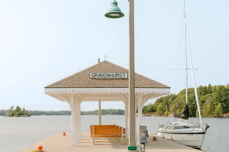 Überdachter Steg mit Blick auf den Lake Muskoka, mit einem Segelboot, das an einem hellen Sommertag neben dem Pier vertäut ist.