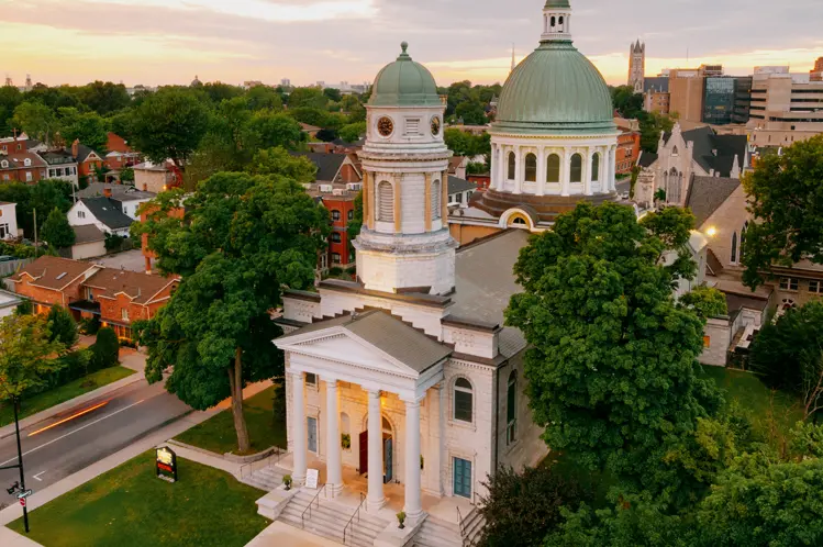 La cathédrale Saint-Georges à Kingston, en Ontario, avec sa tour en forme de dôme s'élevant au-dessus des arbres sous un de coucher de soleil.