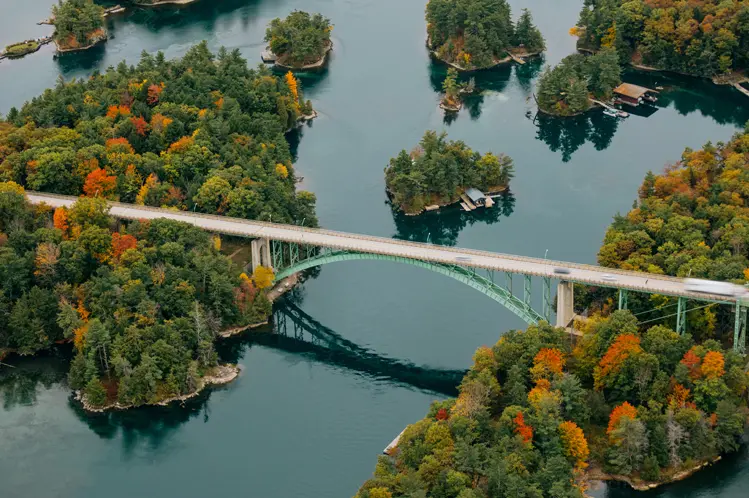 オンタリオ州とニューヨーク州を結ぶサウザンド アイランズ ブリッジ。秋の紅葉と穏やかな水面が美しい森林に覆われた島々を架けています。