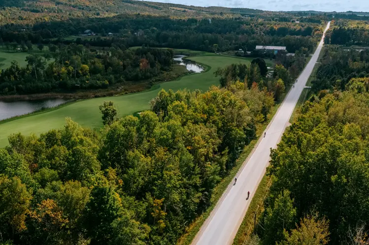 숲과 구불구불한 강이 흐르는 쏜버리의 시골 길을 따라 자전거를 타는 사람들의 모습을 담은 항공 사진입니다. 흐린 여름날의 모습입니다.