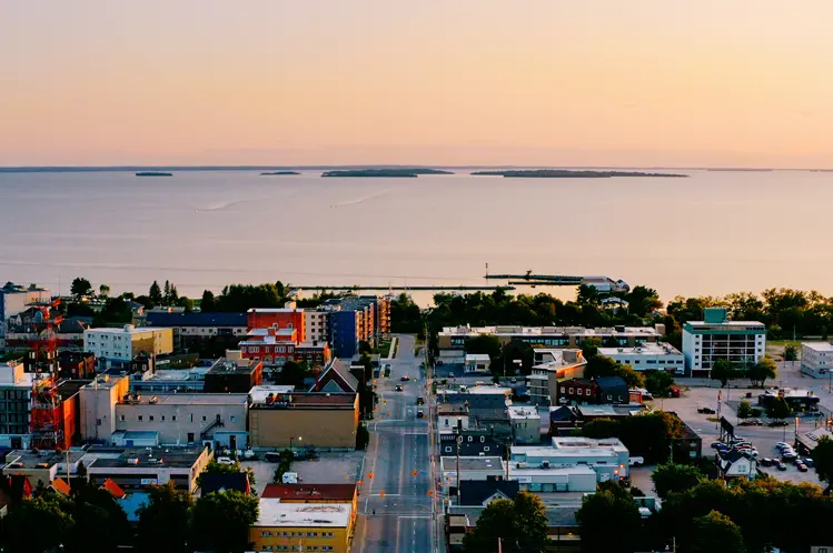 夕暮れ時のノース ベイのダウンタウンの航空写真。遠くに輝くウォーターフロントとマニトウ諸島が見えます。