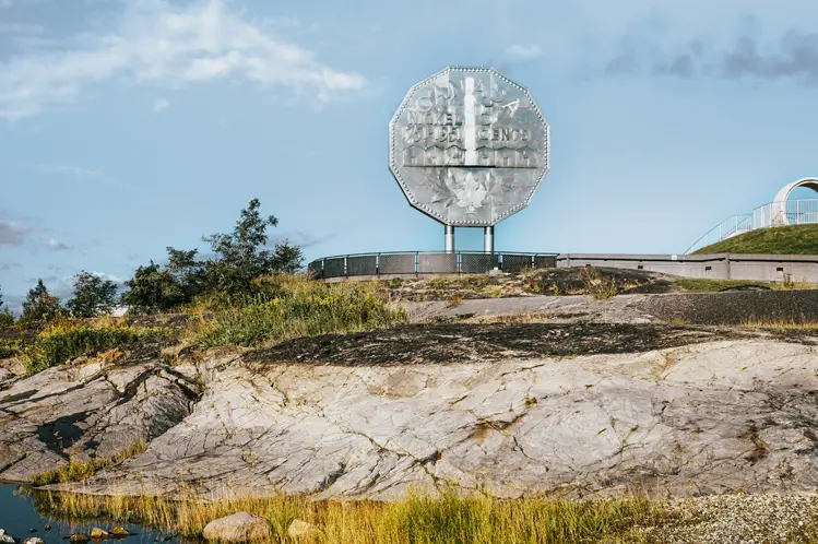 Réplique argentée géante d’une pièce de cinq cents au-dessus d’un terrain rocheux et d’un étang à Terre dynamique, à Sudbury, un jour d’été.