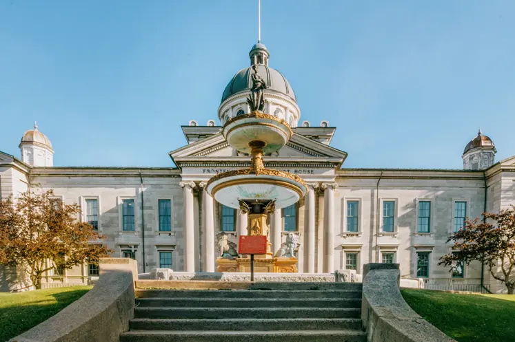 Histórico Palacio de Justicia del condado de Frontenac en Kingston, con techo abovedado y fuente de agua, visto desde la base de amplios escalones de piedra.