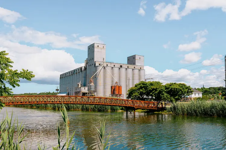 Los silos de grano de Owen Sound y el puente de metal reflejados en el puerto en un soleado día de verano con nubes dispersas.