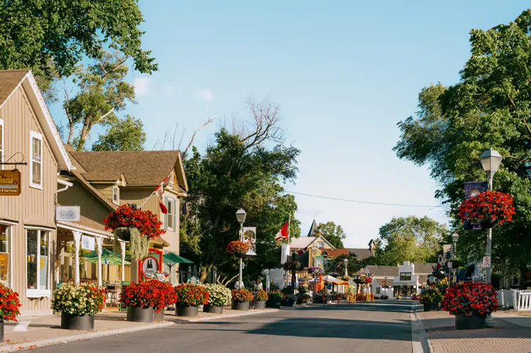 Charming flower-filled main street in Unionville, Ontario, lined with heritage buildings, patios, and boutiques on a sunny day.