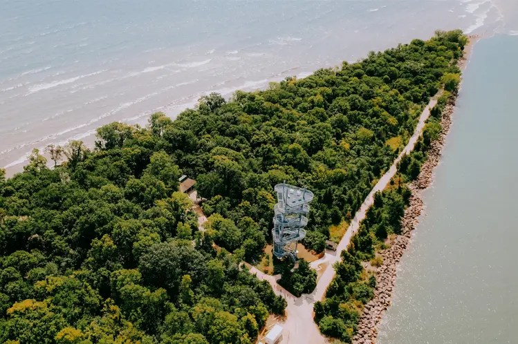 Boardwalk and spiral observation tower winding through lush forest at Point Pelee National Park in Leamington, Ontario, bordered by Lake Erie on both sides.