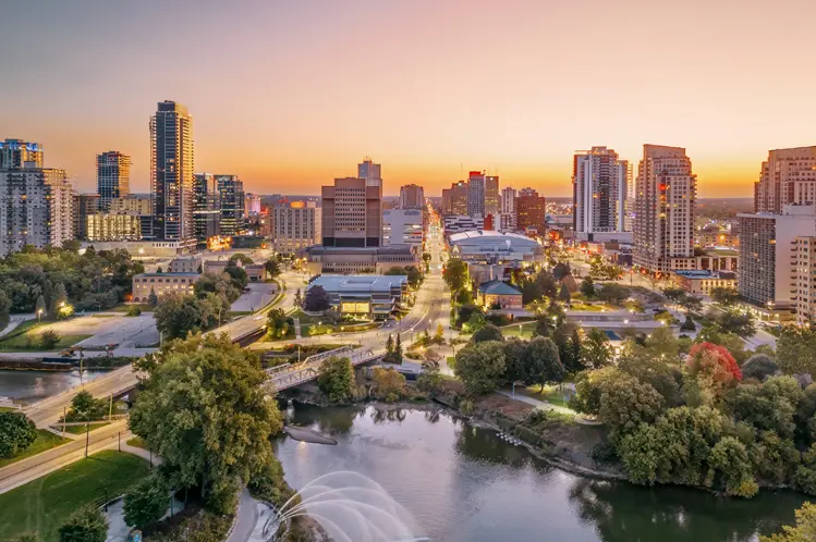 El horizonte de la ciudad de London, Ontario, al atardecer, con el río serpenteando a través de la escena bajo un cielo colorido.