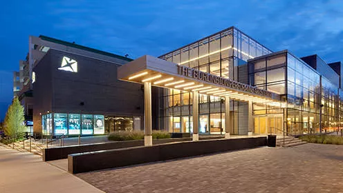 Burlington Performing Arts Centre front entrance. The large building has multiple floor to ceiling windows and stone walls.