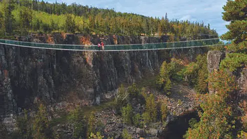 Ein Pärchen steht mitten auf einer Hängebrücke über eine weite Schlucht