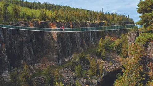 넓은 협곡을 가로지르는 현수교 한가운데 서 있는 커플