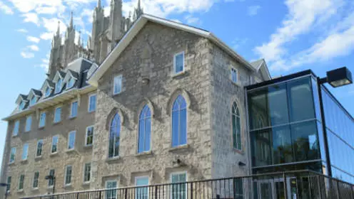 건물 전면에 대형 유리 확장이 있는 개조된 대형 석조 수도원입니다.