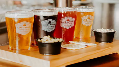Ein Bierflug mit vier Biersorten und Beilagen der Lake of the Woods Brewing Company.