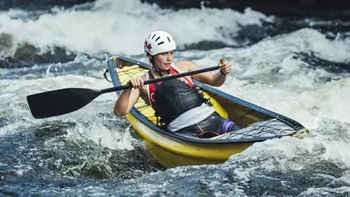 A solo canoeist navigates whitewater rapids