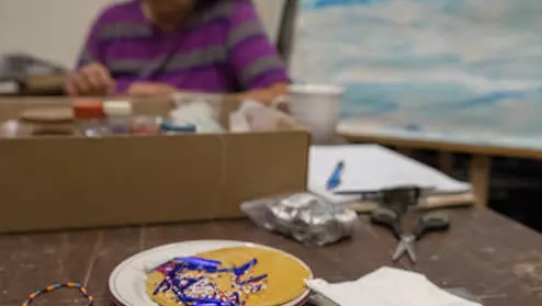 An Ojibwe artist works on crafts in a studio