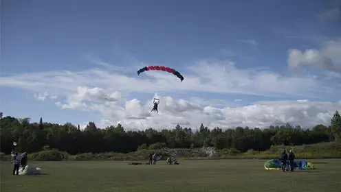 Person parachuting in open grass field
