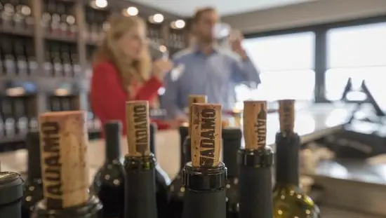 Bouchons sur des bouteilles de vin, tandis qu'un homme et une femme apprécient le vin en arrière-plan