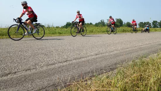 Three cyclists riding on a rural road on a sunny day