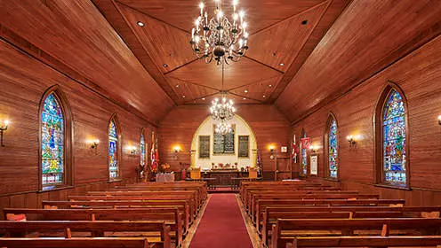 목제 판넬로 덮인 예배당 내부와 양쪽에 3개의 스테인드 글라스 창. 통로는 두 줄의 나무 의자를 분리하고 세 개의 샹들리에가 그 위에 매달려 있습니다.