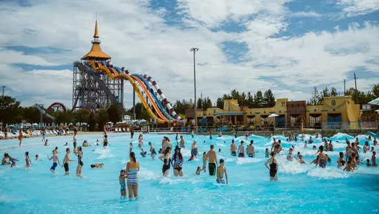 大人と子供でいっぱいの大きなプールで、向こう側にウォータースライドがあります