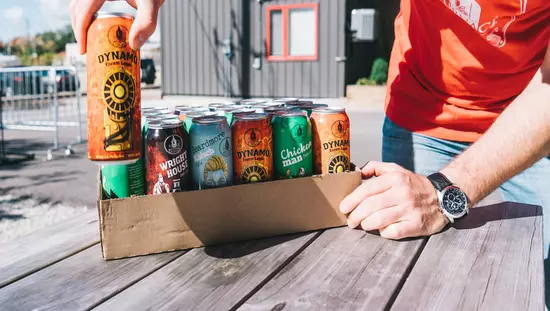 Gentleman packing cans of various kinds of beer outside brewery building