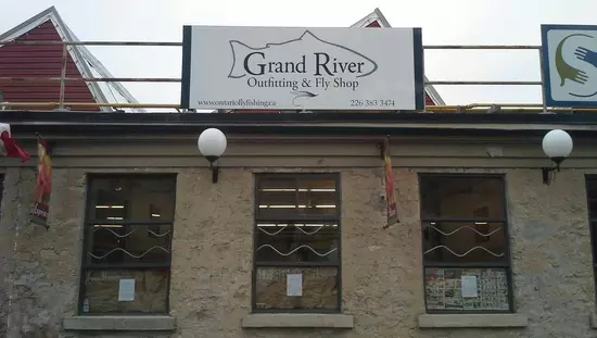 Vue de la devanture d'une boutique avec murs de vieilles pierres et une rangée de trois grandes fenêtres plus haut.