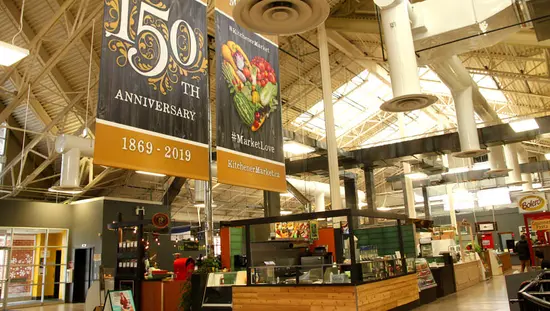 2 Banner hängen über einer Vielzahl von Ständen an der Rückwand, von denen eines das 150-jährige Jubiläum des Marktes ankündigt