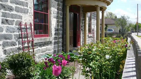 Ángulo de visión del antiguo edificio de ladrillo gris con pórtico en la entrada principal y jardín de tulipanes a lo largo de la pared frontal