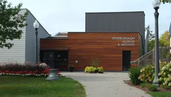 Steinweg, der durch Rasen und Gärten zur Terrasse hinter dem modernen Holzgebäude mit Eingangstüren führt