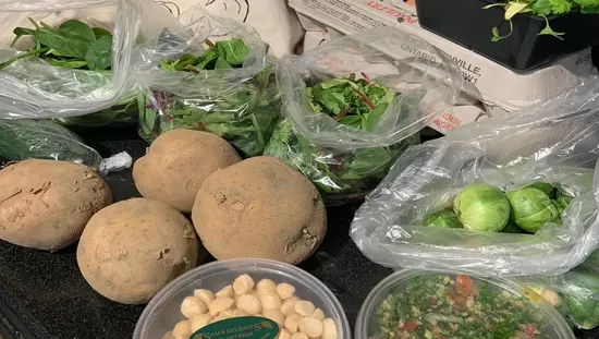 Bolsa de lona de Farmers Market en la mesa con 2 cartones de huevos y varias papas y paquetes de varias verduras verdes