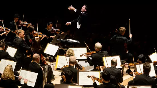 Ein Dirigent steht während einer Aufführung vor seinem Orchester
