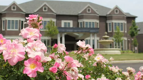 앞 잔디밭에 둥근 석조 분수가 있는 대형 유산 호텔 전경과 멀리 있는 분홍색 꽃