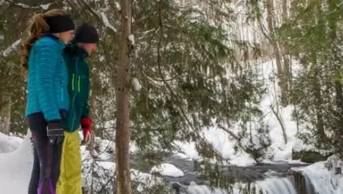 A couple snow shoeing and looking down at the ground