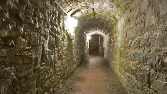 Un chemin sombre et effrayant mène à travers un vieux tunnel en pierre