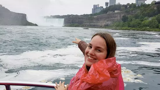 A young girl on a boat pointing at the Niagara Falls landscape