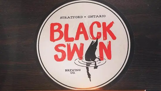 Fotografía cenital de un vuelo de cuatro colores diferentes de cervezas, frente al logotipo de Black Swan