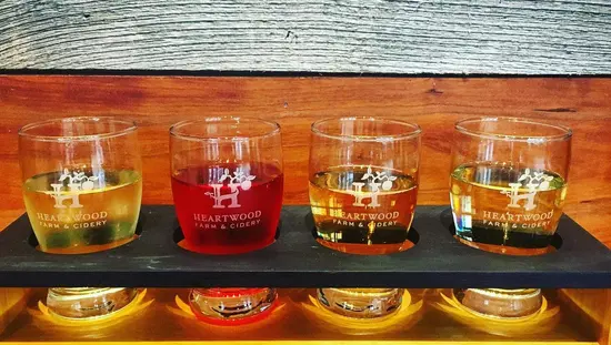 A flight of 4 ciders sitting on a wood table