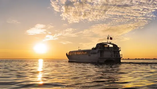 A sunset behind a boat that is cruising the waters